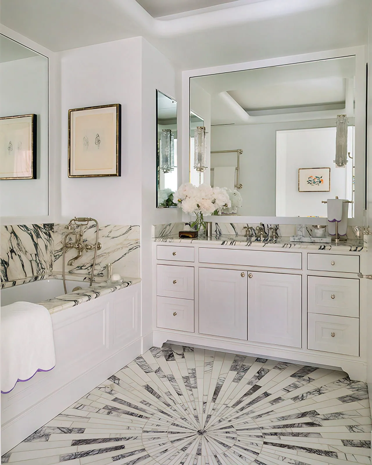 White marble primary bathroom with double vanity, mirrored walls, and a radial patterned stone floor.